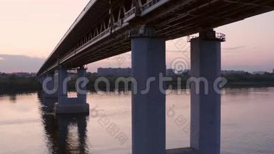 车在镜城河上的桥上行驶。 日落背景下驾驶桥上的汽车行驶